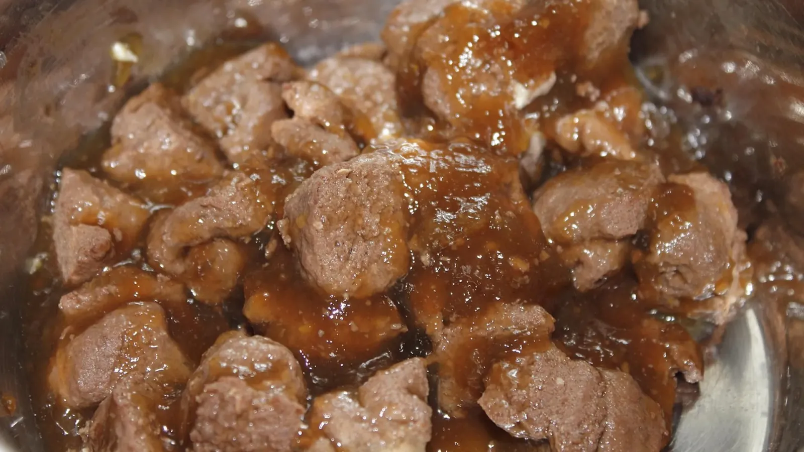 Nassfutter-Stücke in Soße in einem Edelstahlnapf – Symbolbild zur Haltbarkeit von geöffnetem Nassfutter und zur richtigen Lagerung von Tierfutter